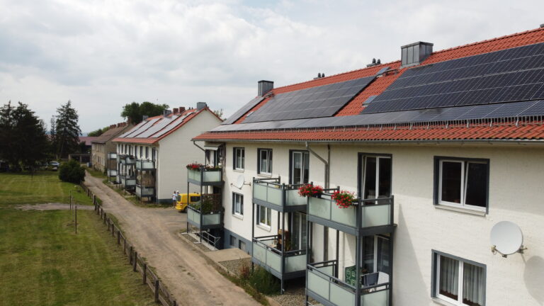 Luftaufnahme eines Mehrfamilienhauses mit Photovoltaikanlage auf dem Dach
